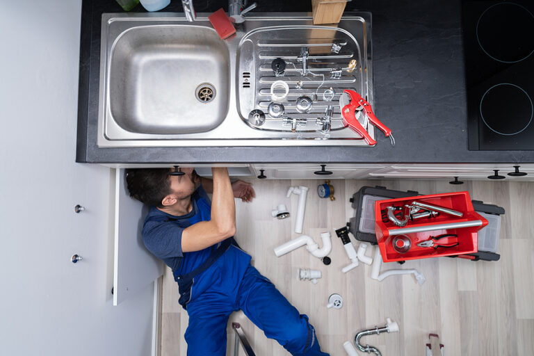 A plumber working on a kitchen sink.