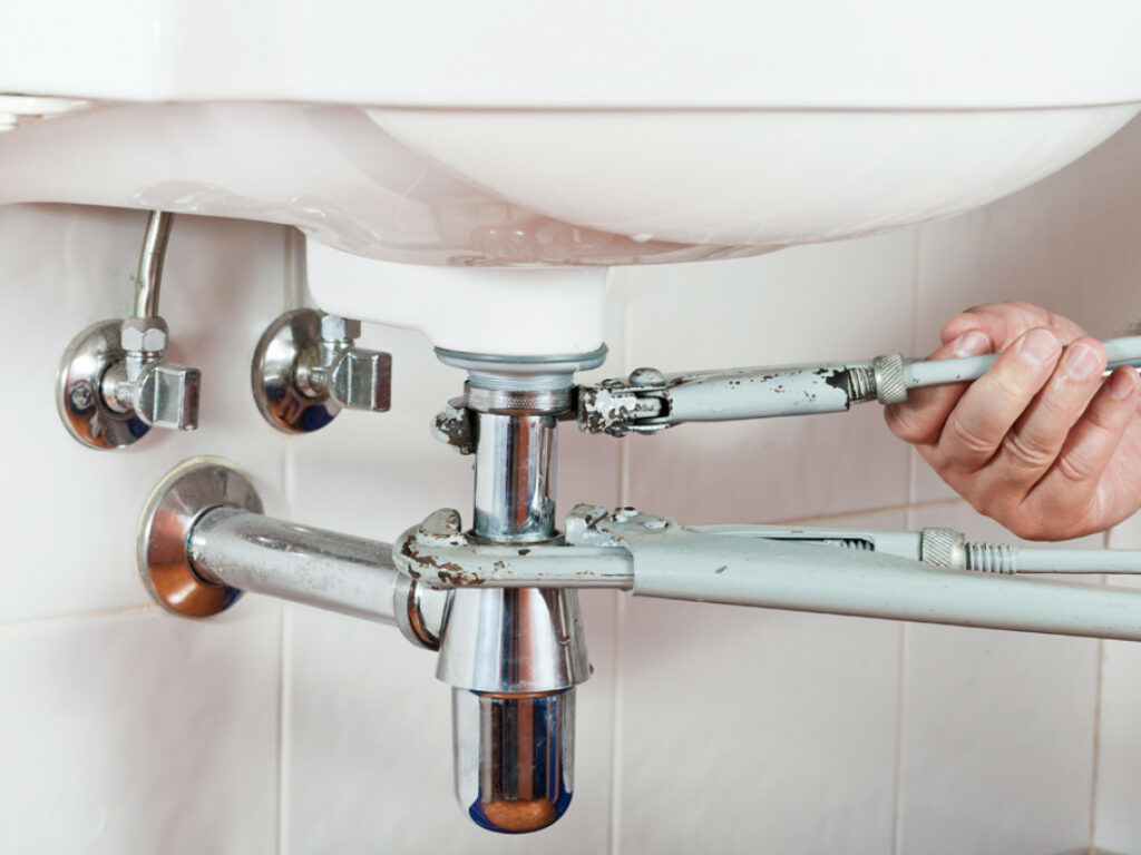 A plumber repairing a leaky sink drain.