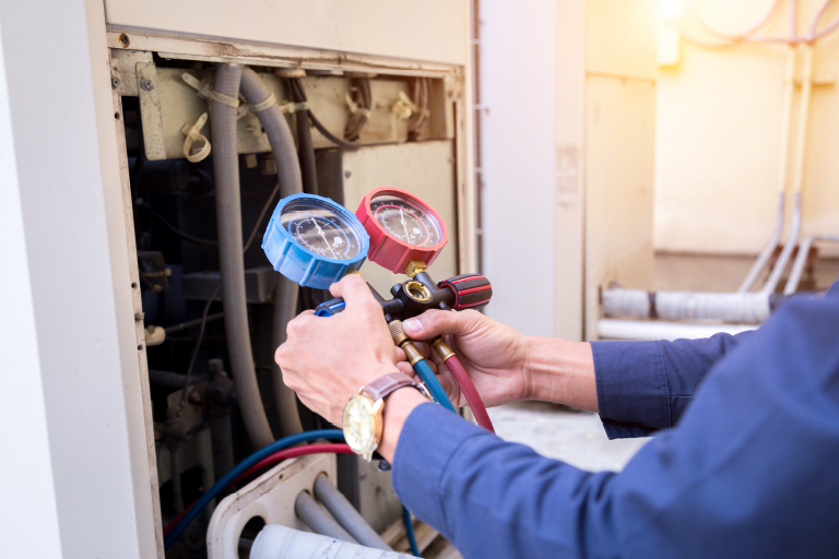 hvac technician looking at red and blue gauges