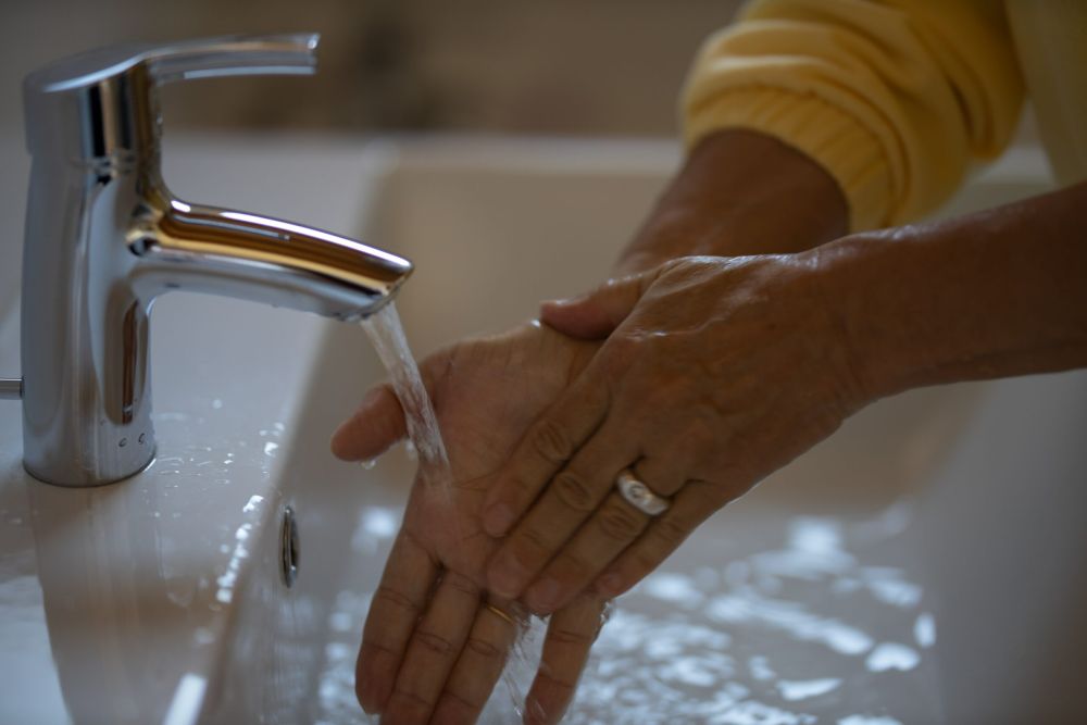 Woman washing hands with hot water at bathroom sink.